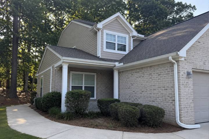 Two story Georgia home with clean white gutters and downspouts in a pine shaded yard in morning light