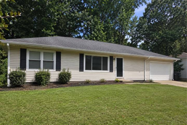 Long white gutter run across the front of a Georgia ranch home framed by tall shade trees